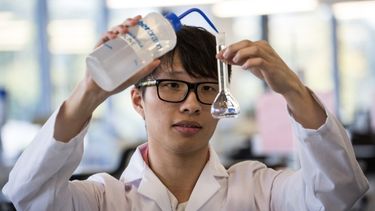 Male Student Doing Experiment In Laboratory