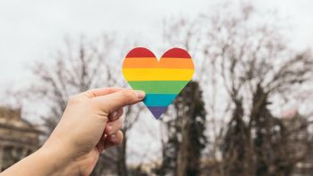 Hand holding paper heart in rainbow colours