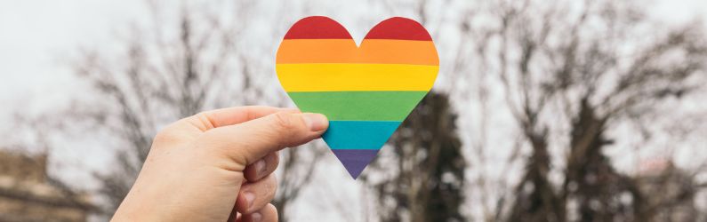 Hand holding paper heart in rainbow colours