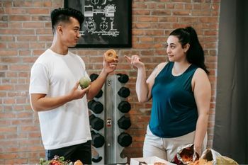 Two people in a gym deciding if they should eat a donut.