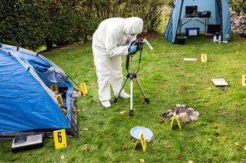 A single forensic scientist out in the field taking photos of a crime scene.