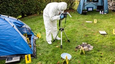 A single forensic scientist out in the field taking photos of a crime scene.